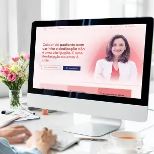 imagem de um computador em cima de uma mesa  e um jarro de flores.